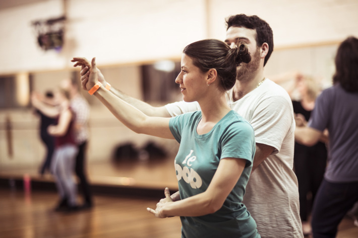 A couple holding hands dancing in a studio.