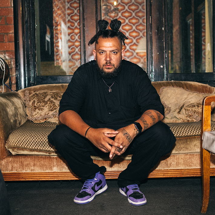 A photo of Kiwat Kennell sitting on a vintage couch