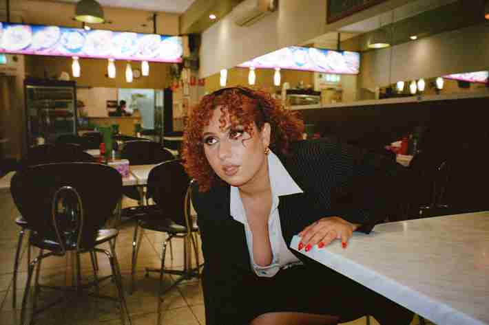 Yara in an office outfit sitting at a restaurant table