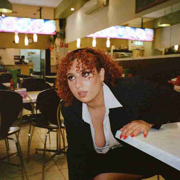 Yara in an office outfit sitting at a restaurant table