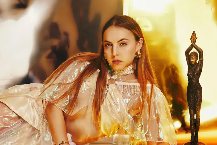 Image shows Alethia lying on the ground with orange and yellow tones.