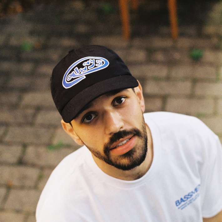 Name UL star up directly to the camera wearing a white t-shirt and a black cap that reads 'always' on the front
