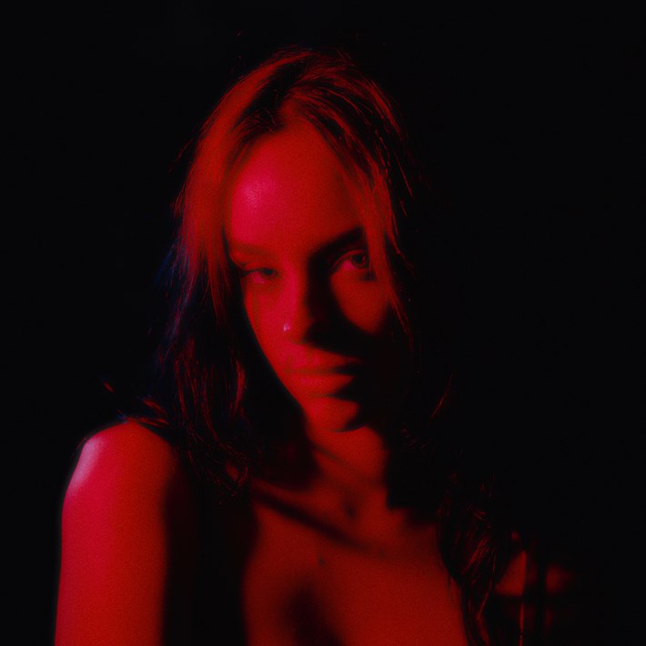 Mathilde Anne looking at the camera with a soft red light glowing over her face.