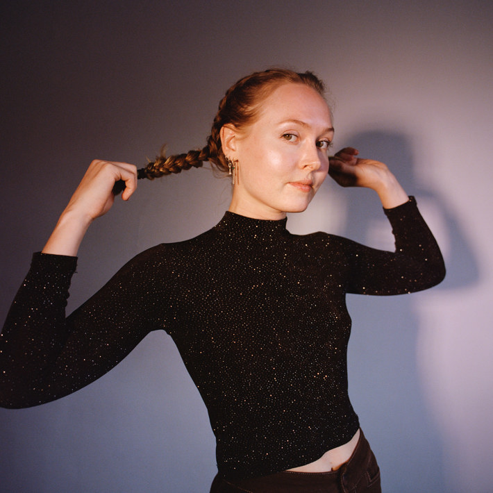 A woman pulling the long braids in her hair, looking confident.