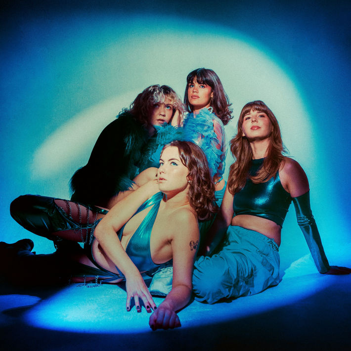 Four people sitting on the ground covered in a cool blue light